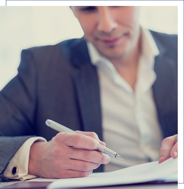 A man in suit writing on paper with pen.